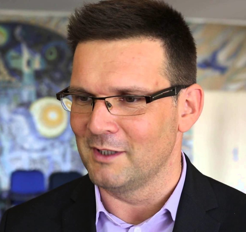 Zoltán Birkner portréja szemüveggel és öltönnyel. Komoly, professzionális megjelenés.