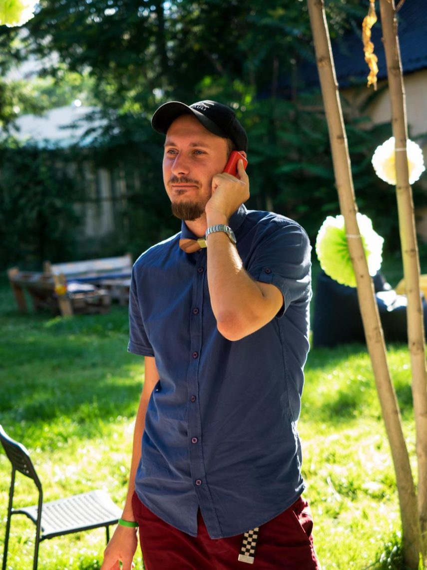 Filip Lyapov telefonál a kertben. Kék ing, fekete sapka.