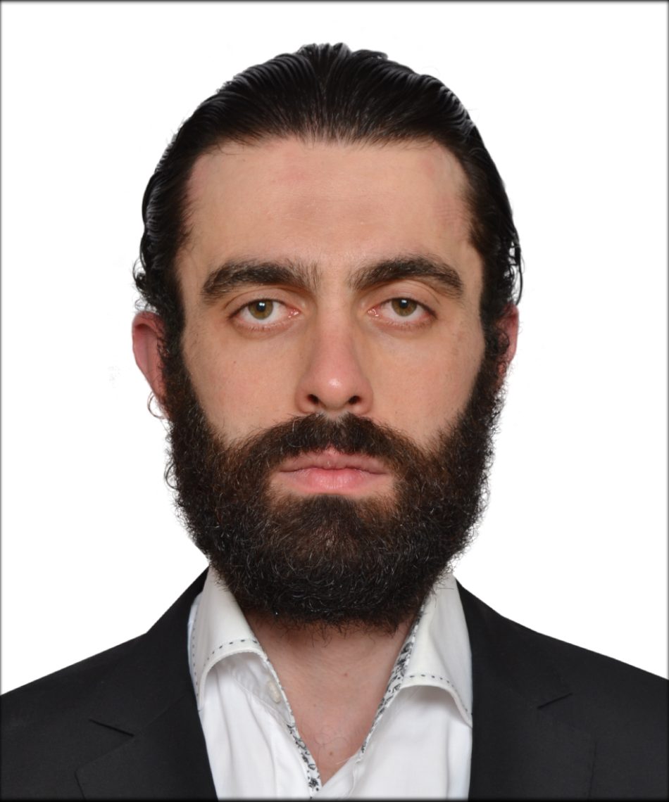 Hüsamettin U. Öztürk portréja fekete öltönyben és szakállal.