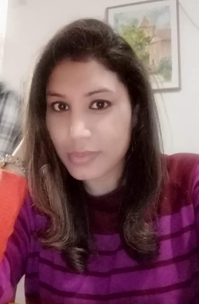 Farzana Christopher portréja lila csíkos pulóverben, barna hajjal.