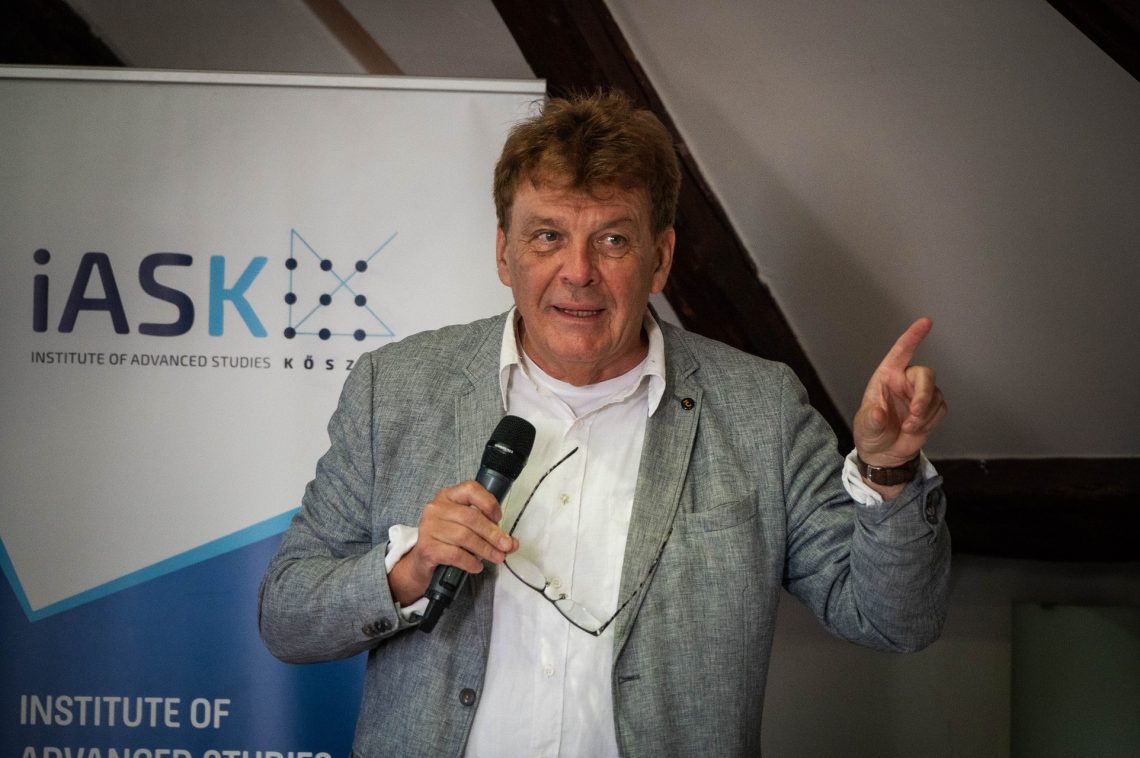 Férfi előadást tart a Kőszegi Nemzetközi Nyári Egyetemen. iASK logó látható.