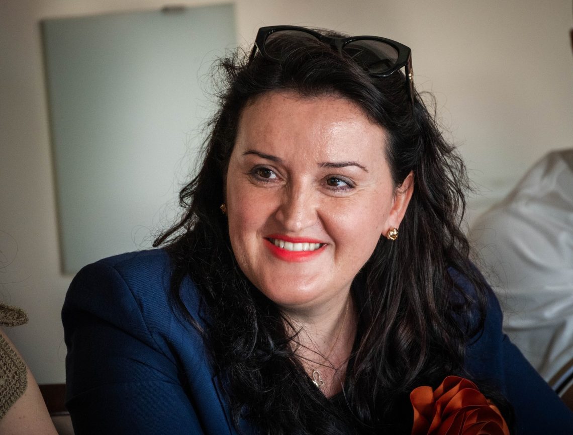 Mosolygó nő kék blézerben, a Kőszegi Nemzetközi Nyári Egyetem résztvevője.