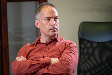 Krekó Péter portréja, karba tett kézzel, komoly arckifejezéssel.