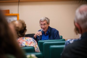 Könyvbemutató: Katona Attila beszél mikrofonba, közönség hallgatja. "Csillogás és katasztrófa" esemény.