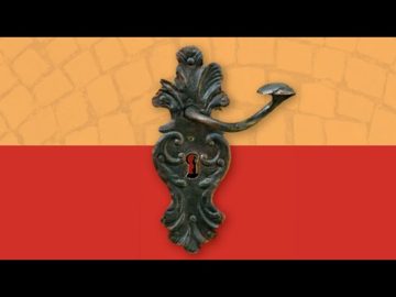 Díszes kovácsoltvas ajtókilincs texturált piros és narancssárga falon