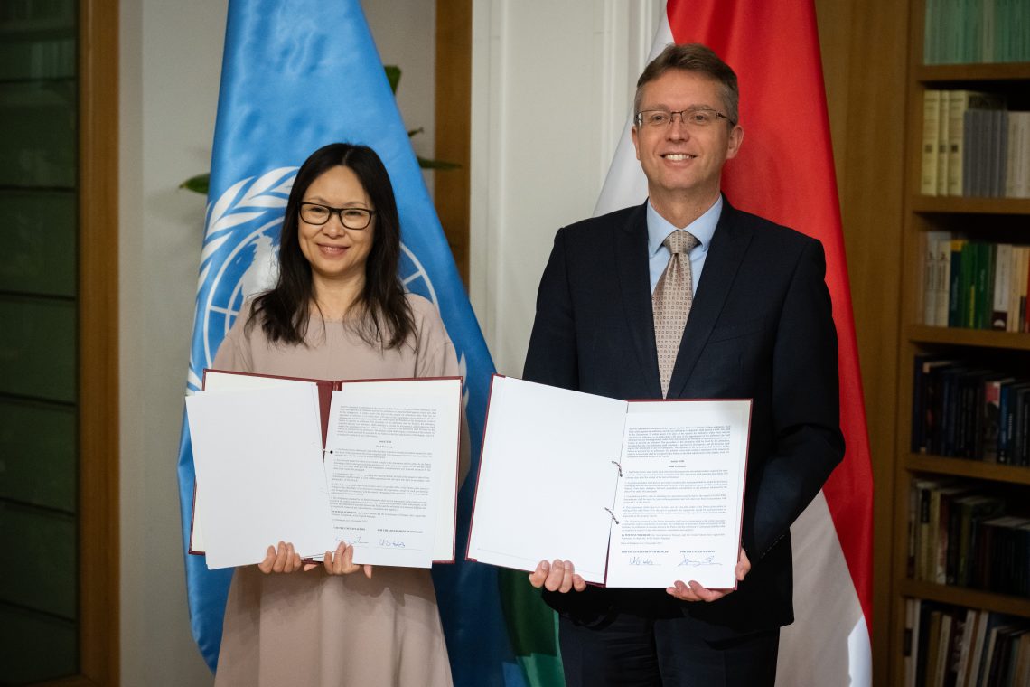 Egyezmény aláírása Kőszegen az ENSZ Egyetem új intézetének létrehozásáról. ENSZ zászló és magyar zászló látható.