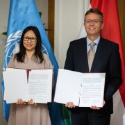 Egyezmény aláírása Kőszegen az ENSZ Egyetem új intézetének létrehozásáról. ENSZ zászló és magyar zászló látható.