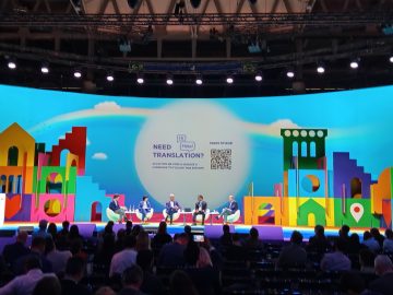 Közönség az iASK Smart City Expo Világkongresszus barcelonai színpadán. "Need Translation?" felirat.