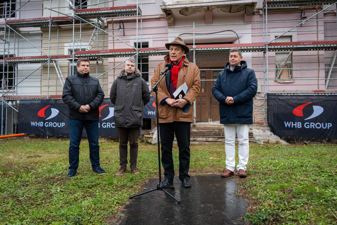 Kőszeg: Férfiak az ENSZ Egyetem új Campusának építkezésénél. WHB Group logó.