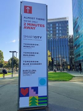 Barcelona Smart City Expo Világkongresszus tábla: "Már majdnem ott vagyunk! Csak 2 perc" felirattal.