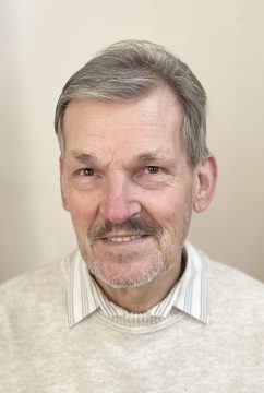 Thuróczy Csaba portréja, mosolygós, szürke hajú férfi