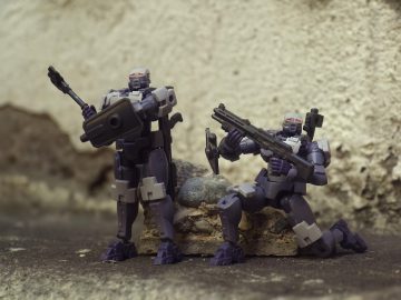 Két robotfigura fegyverekkel, a "Climate BioStress Sentinel System" témához kapcsolódóan.