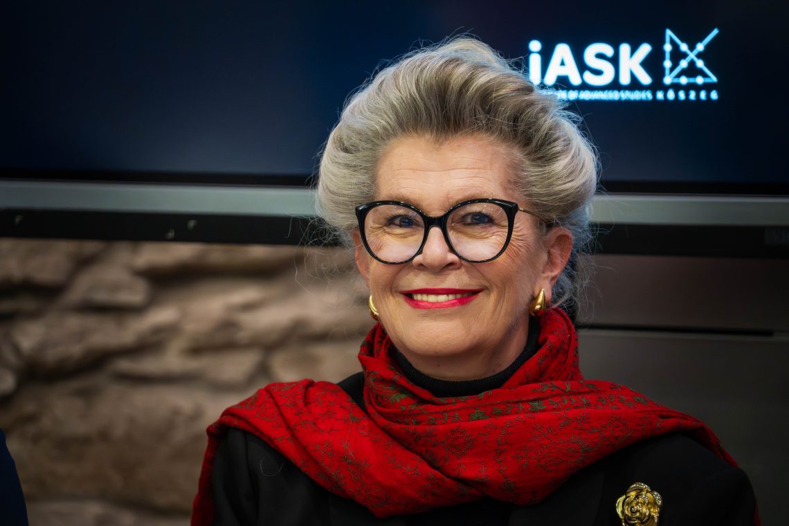 Bogyay Katalin Kőszegen, az iASK logóval a háttérben.